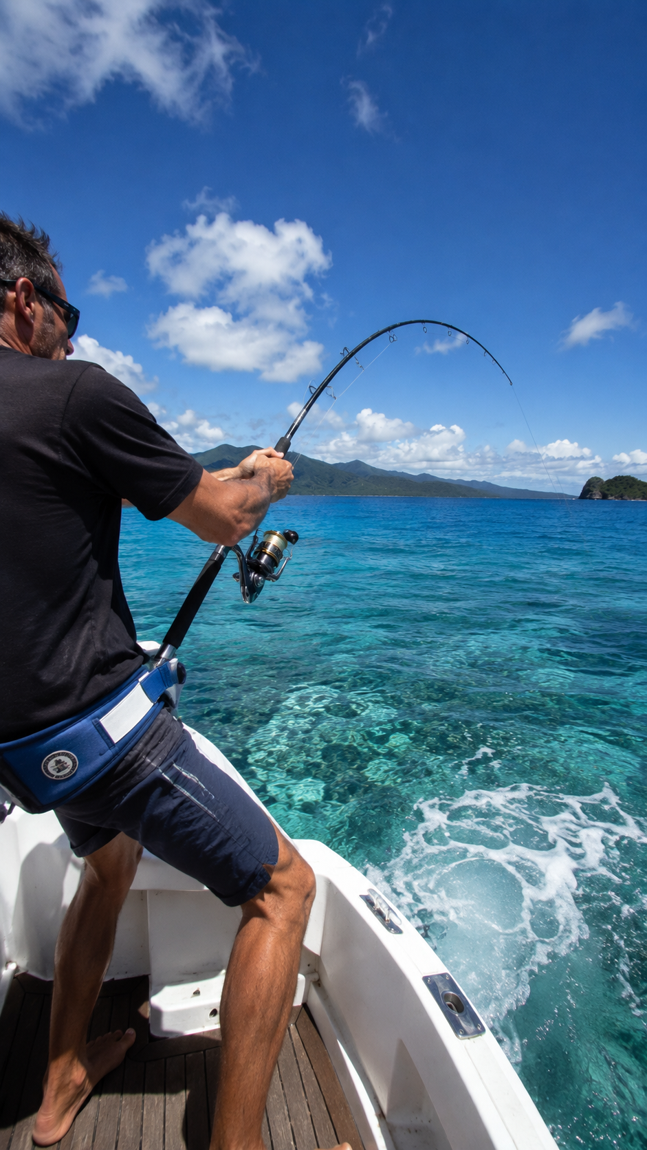 Angler on a boat holding a bent fishing rod in the New Caledonia lagoon